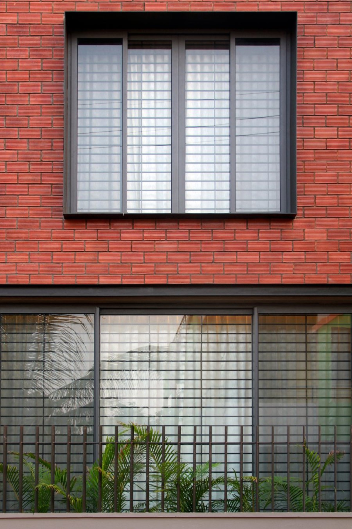 Steel Plate Window Frame of Corner Brick House by Jacob + Rathodi Architects