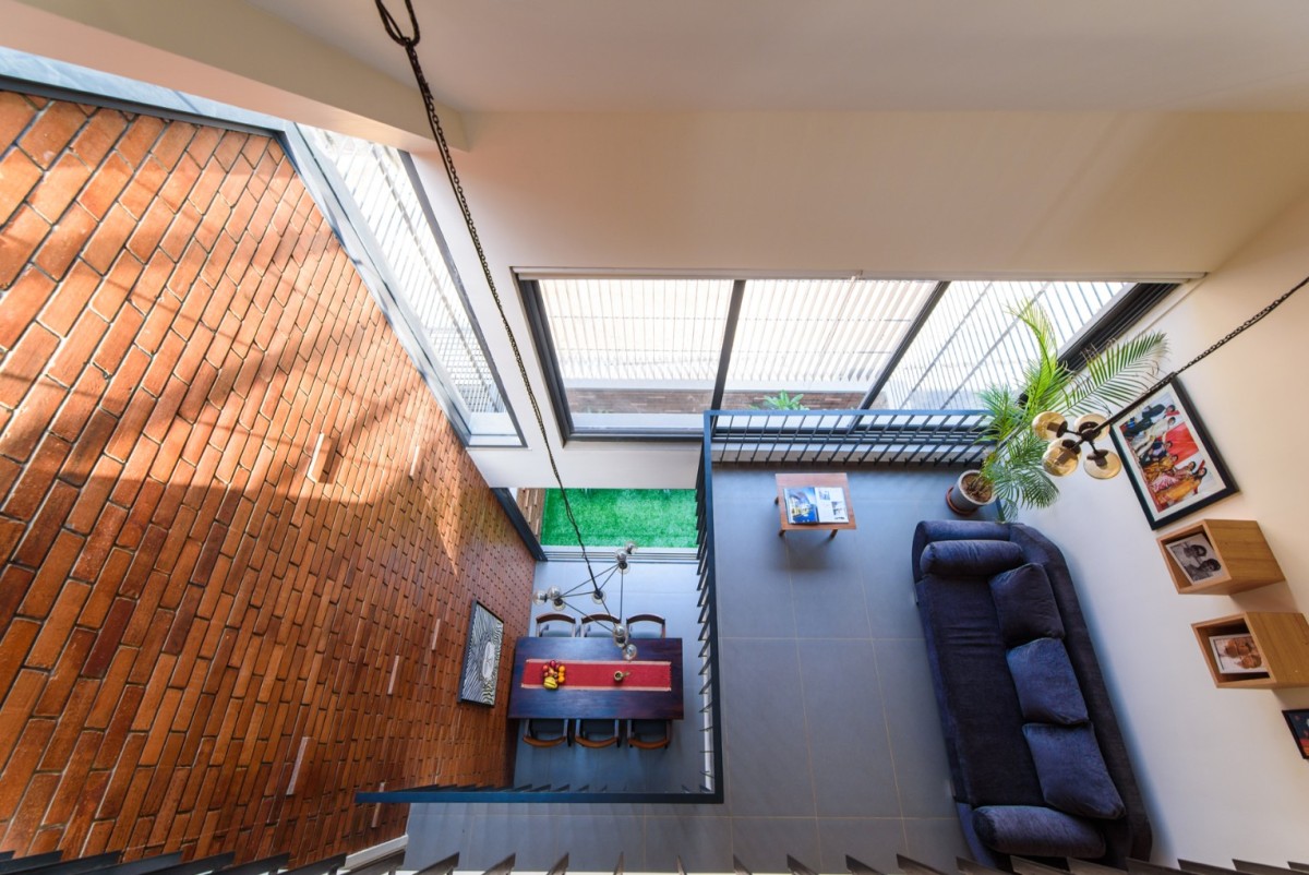 Bird's eye view of central triple height void from terrace bridge of Corner Brick House by Jacob + Rathodi Architects