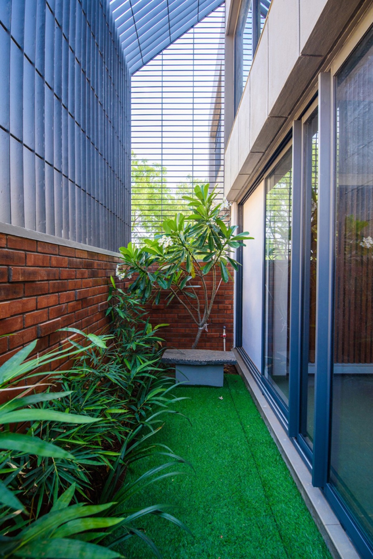 Landscape Courtyard of Corner Brick House by Jacob + Rathodi Architects
