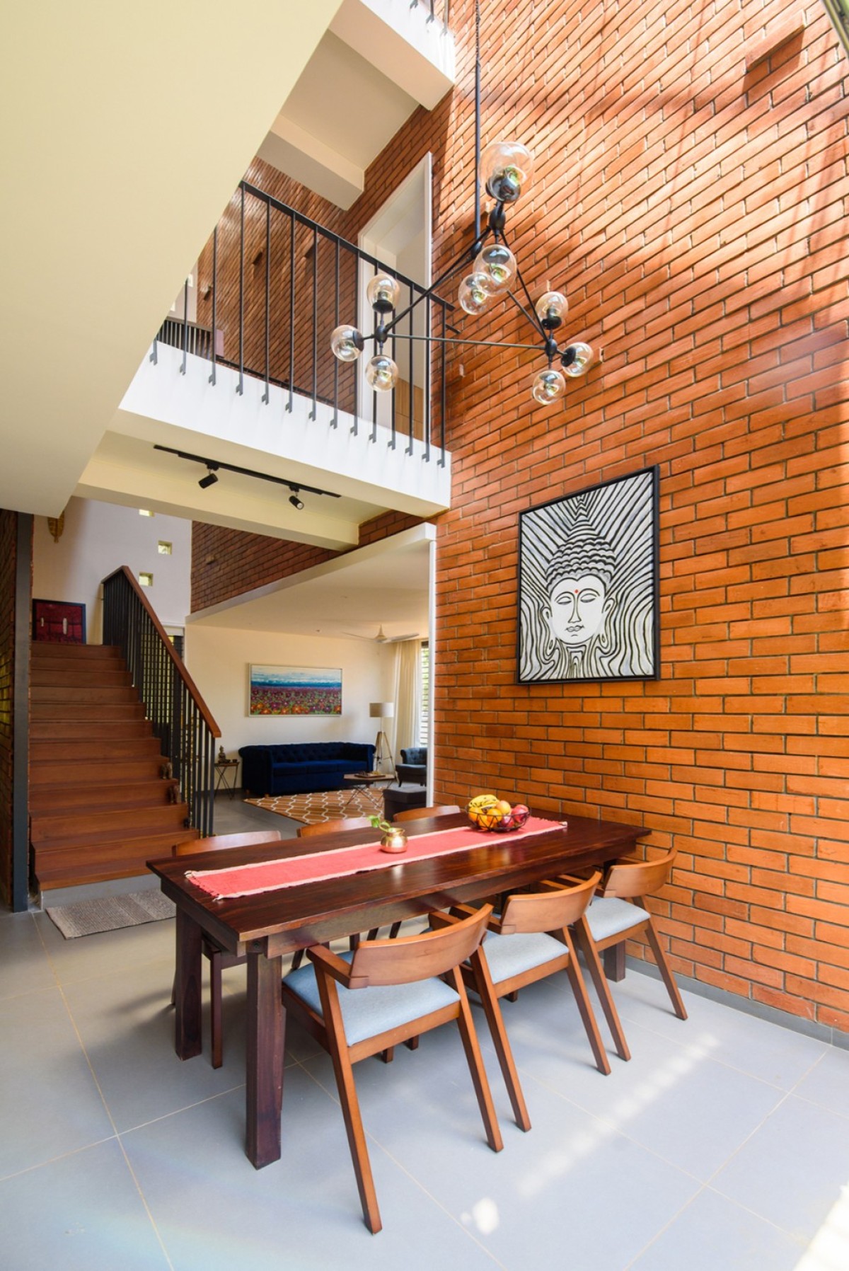 Dining located under a triple height void of Corner Brick House by Jacob + Rathodi Architects