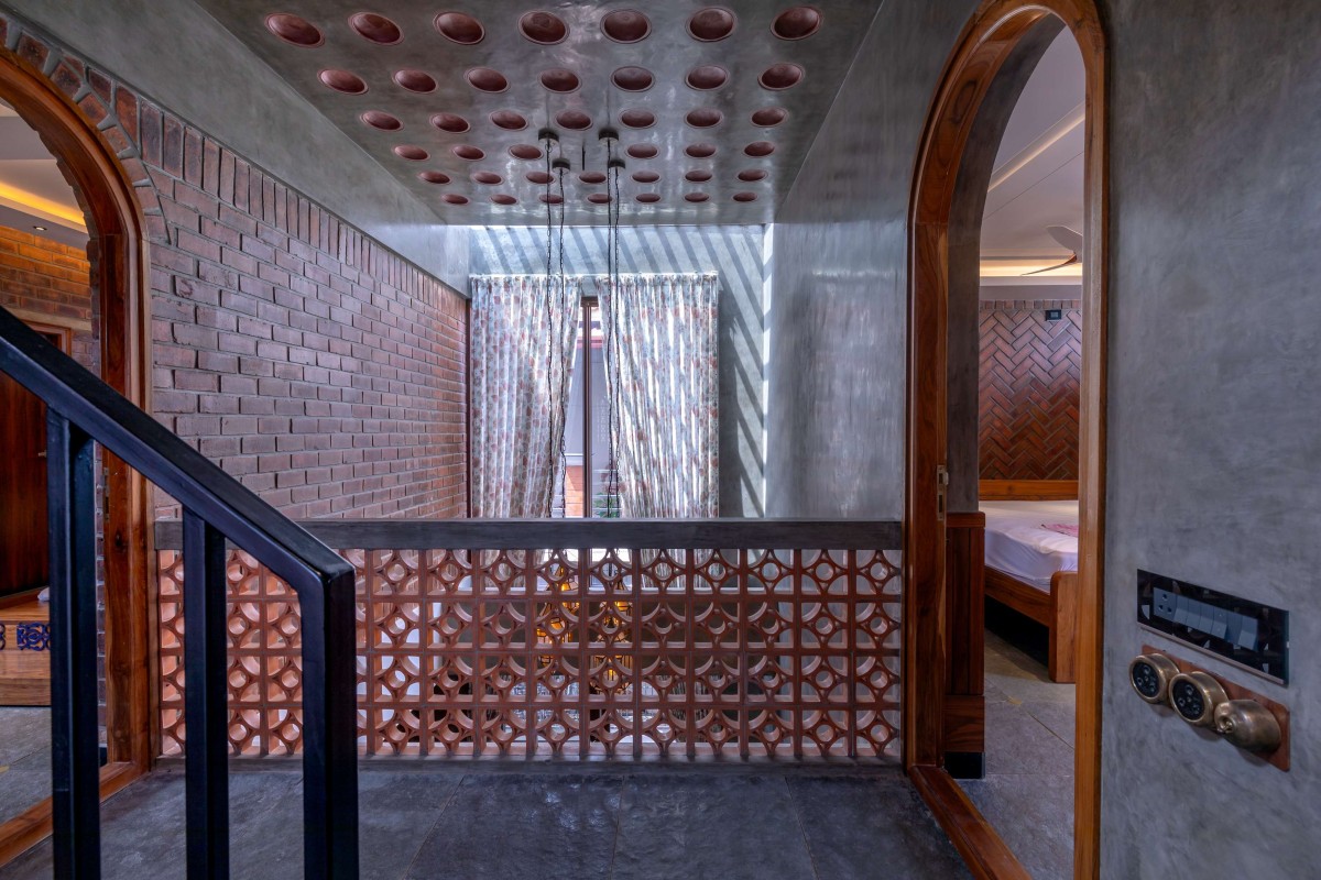 The railing for the landing at the second level is done with Nuvocotto terracotta jaali tiles, topped by a concrete handrail finished in grey oxide – Kuteeram by Brick and Compass