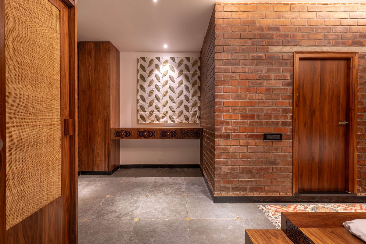 Guest bedroom on the second floor is anchored by an inbuilt floor-mounted bed in teak wood, whose headboard extends into panelling on the walls – Kuteerm by Brick and Compass