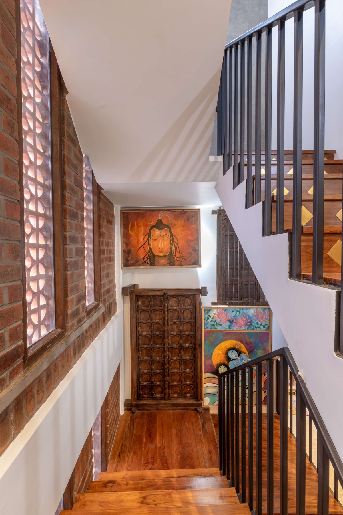 Paintings of Krishna, Shiva and antique doors sourced from Jodhpur bring in character to the staircase wall – Kuteeram by Brick and Compass