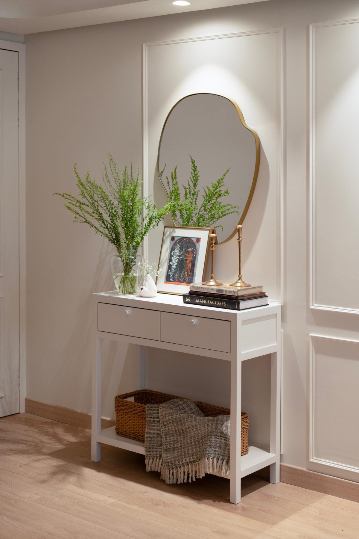 An egg shell custom console with asymmetrical mirror in brass frame of Maison Blanche by Oris Architects