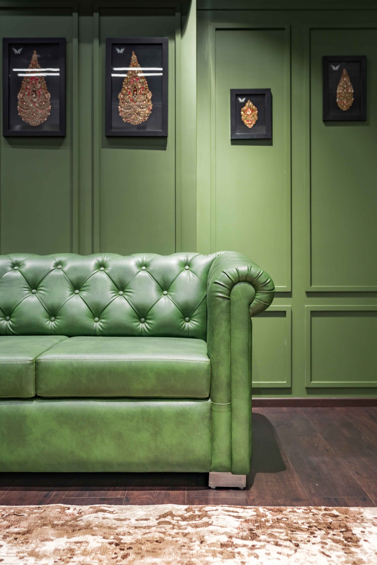 Green upholstered sofa with a backdrop of emerald green MDF Wall