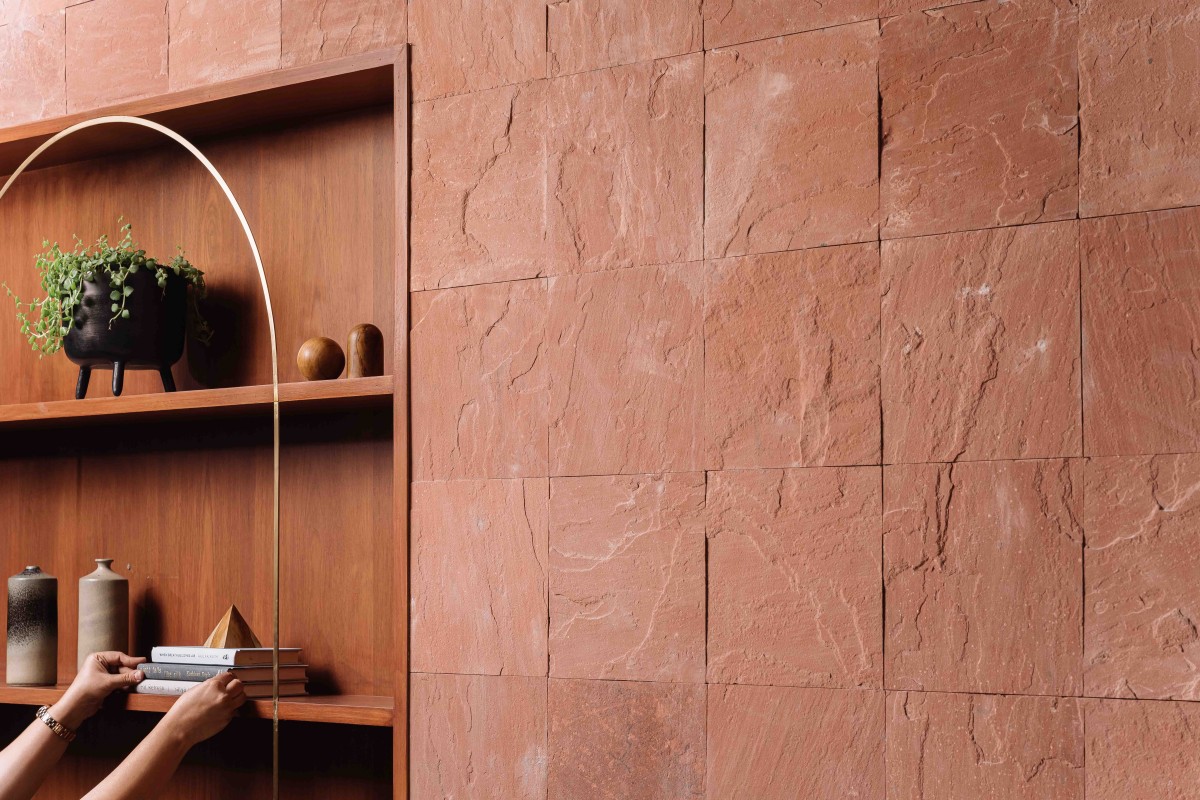 Wooden niche with brass element compliment the reddish stone thus highlighting the entire wall