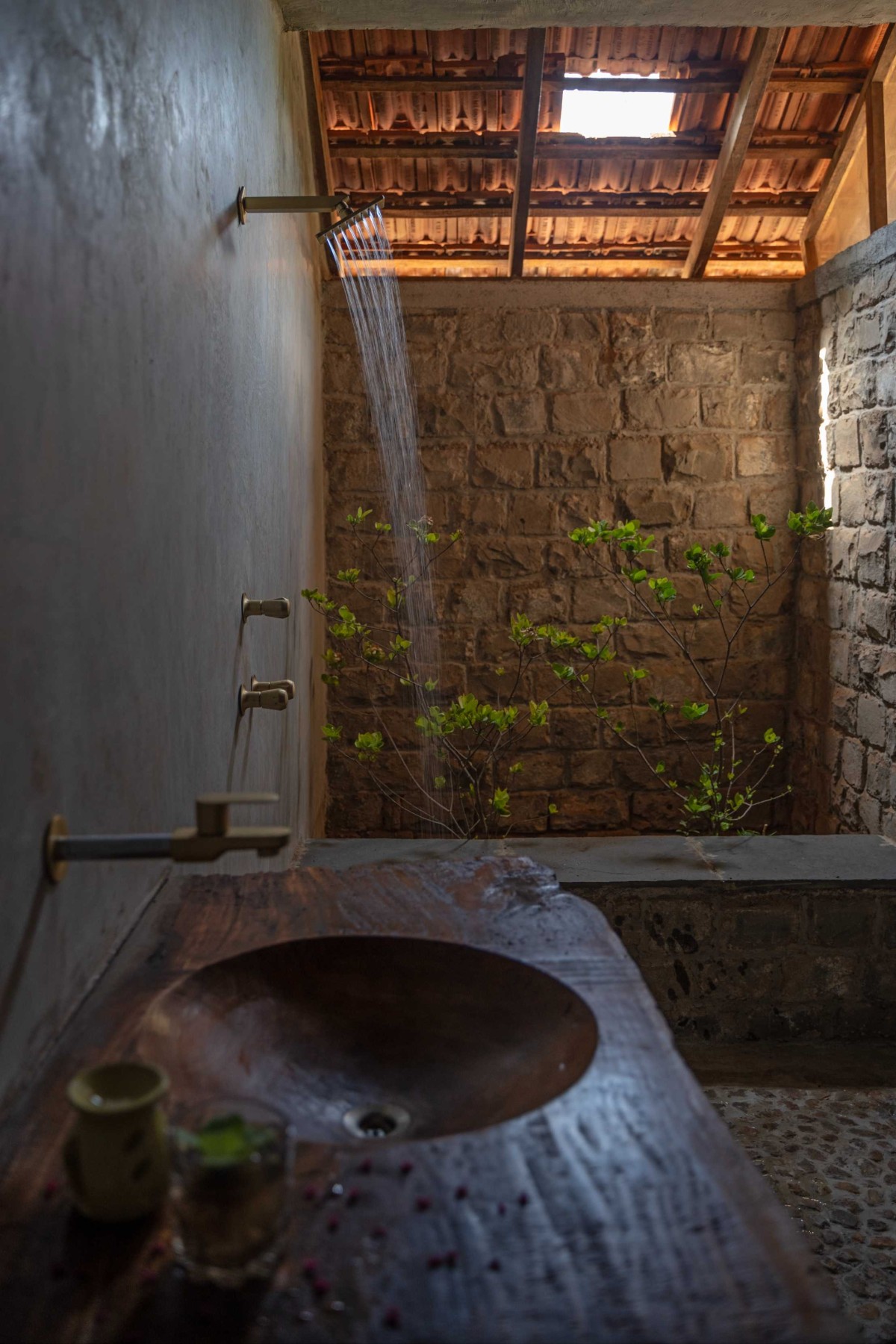 Master bathroom with handcrafted wash basin & pebble floor of House of Reclaimed Gold by Out Of The Box