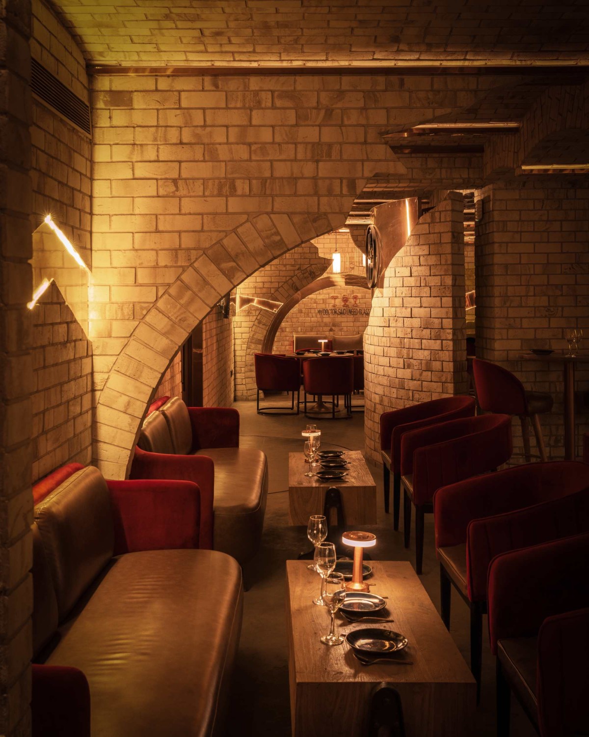 The cracked stone wall revealing copper accents and the low-height jack arches serve as the backdrop for the seating area