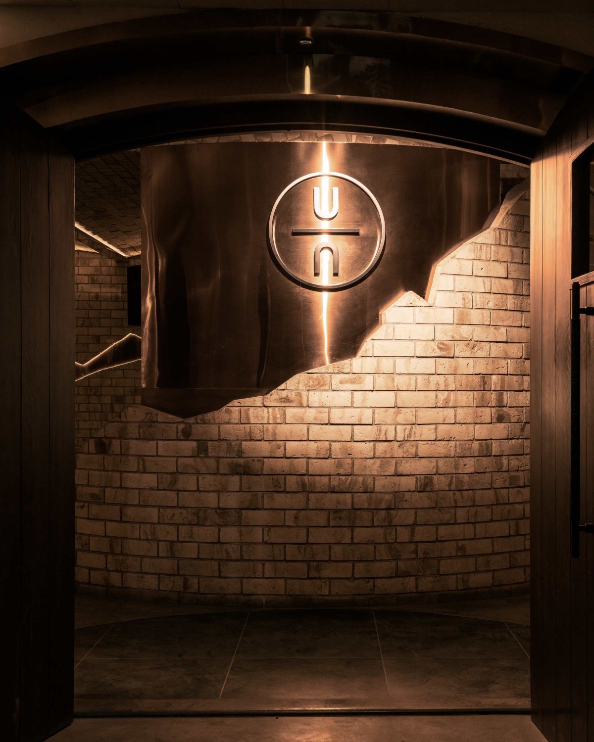 The entrance wall featuring the logo on exposed copper wall, the broken stone wall exposing the copper accents